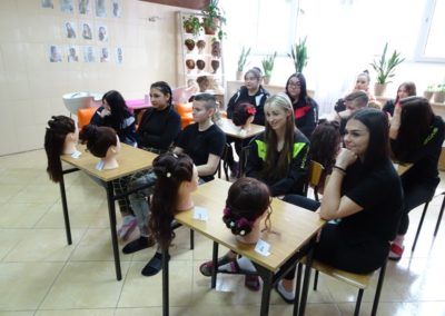 Wychowanki siedzą w ławkach podczas podsumowania konkursu fryzur.